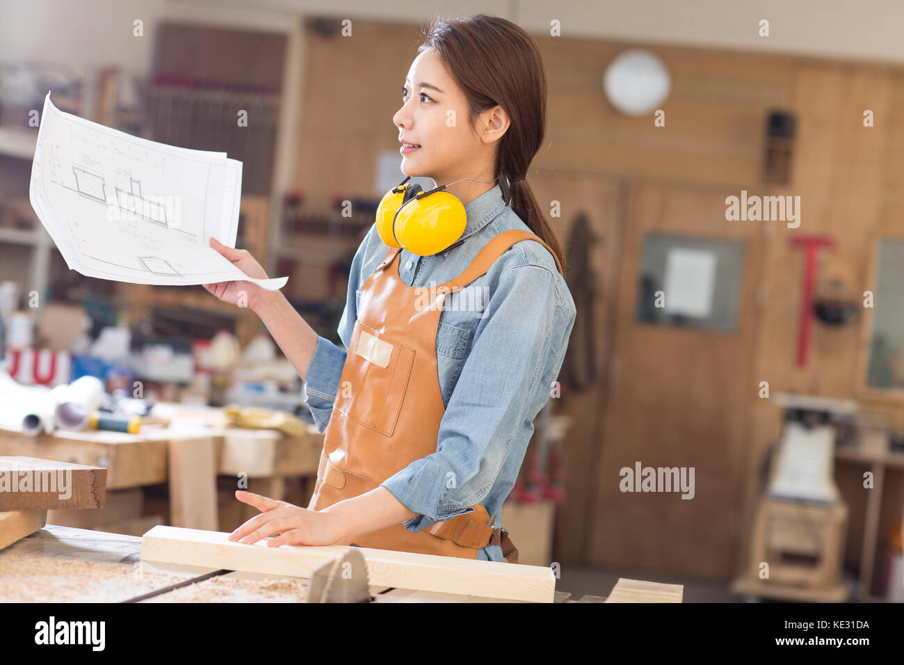 Seitenansicht des Jungen lächelnd weibliche woodworker Holding Blueprint Stockfoto