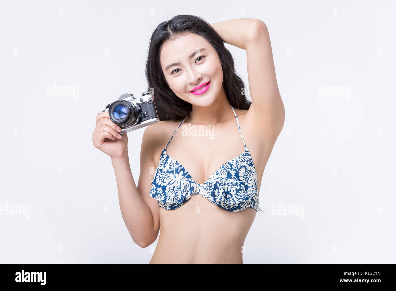 Portrait der junge lächelnde schlanke Frau im Bikini mit einer Kamera posieren Stockfoto
