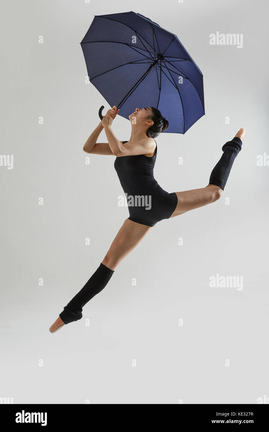 Seitenansicht der junge lächelnde Ballerina in schwarz Body springen  elegant Holding einen Regenschirm Stockfotografie - Alamy