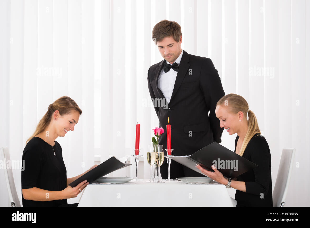 Junge Glücklich weibliche Freunde im Menü im Restaurant mit einem Glas Wein auf Tisch Stockfoto