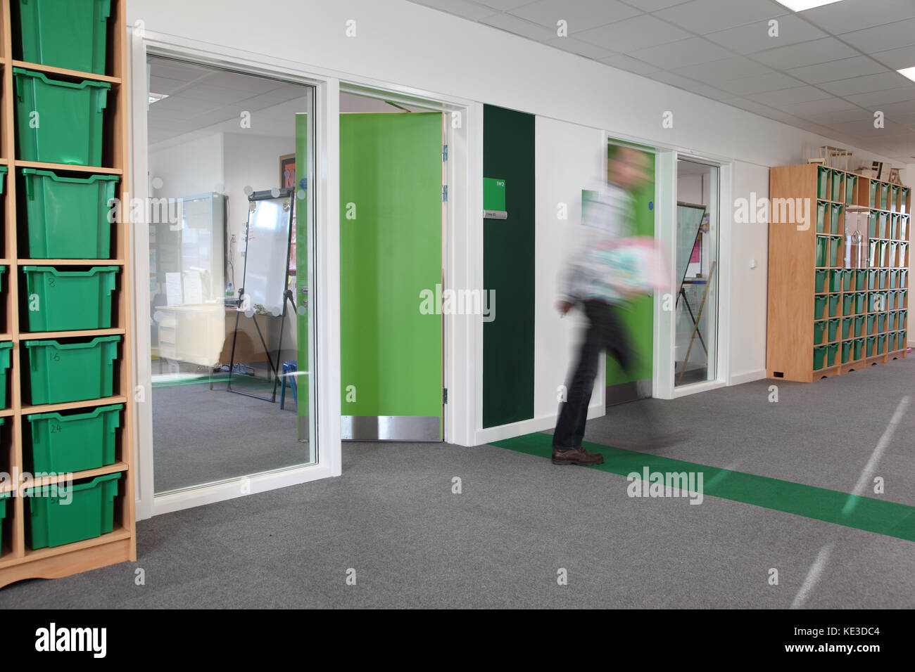 Farbcodierte Klassenzimmer Korridor in einem neuen London Grundschule. Zeigt Lehrer verlassen Klassenzimmer - durch Bewegung verwischt. Stockfoto