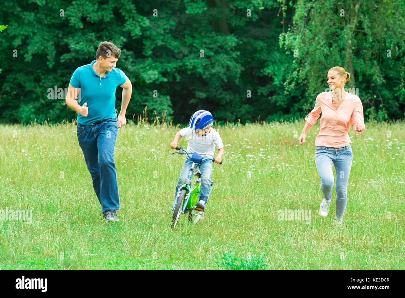 Glückliche Eltern, die mit ihrem Sohn auf einem Fahrrad im Park Stockfoto