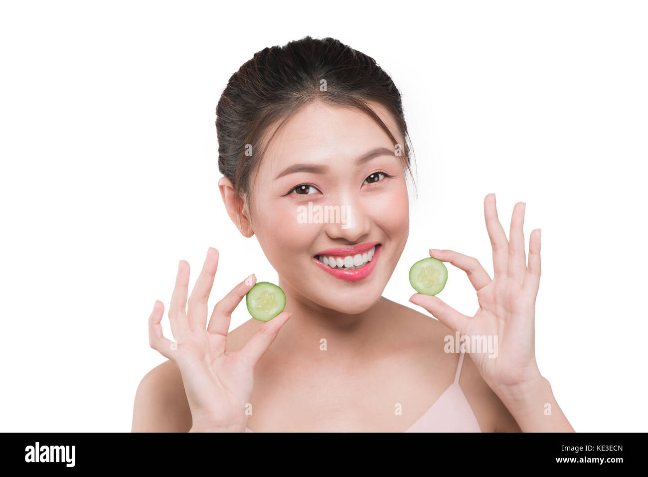 Schöne junge asiatische Frau mit Gurkenscheiben Stockfoto