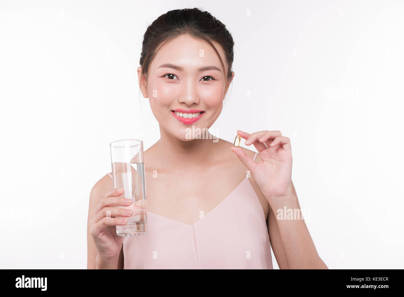 Lächelnd asiatische Frau essen Pillen und Trinkwasser Stockfoto
