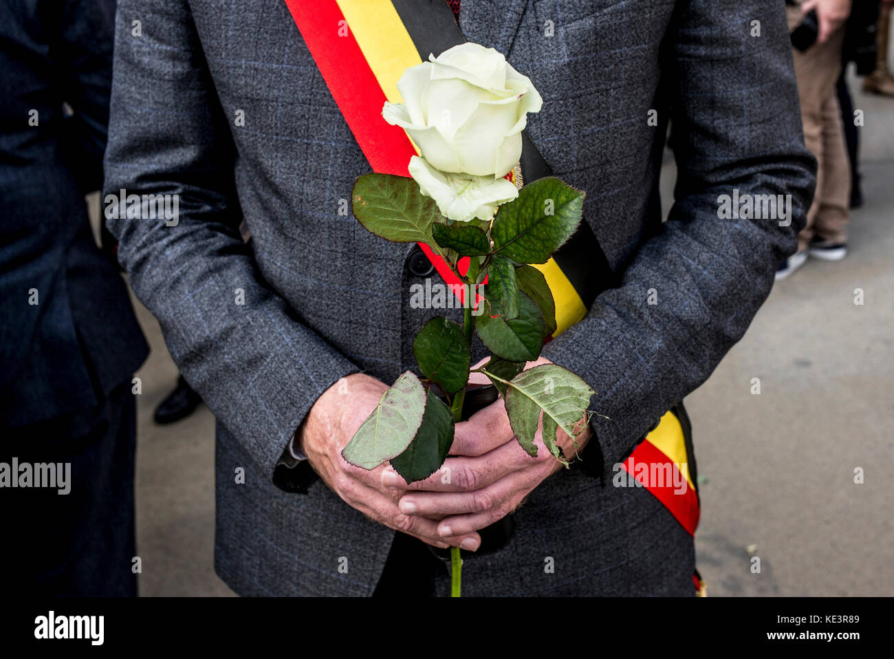 Brüssel, Belgien Oktober 2017. Ein Mann, der mit einem Band in den Nationalfarben Belgiens bedeckt ist, hält eine weiße Rose, während er am Europäischen marsch zu Ehren der Terrorismusopfer und der Rettungsdienste in Brüssel, Belgien am 18.10.2017 von Wiktor Dabkowski teilnimmt | Verwendung weltweit Credit: dpa Picture Alliance/Alamy Live News Stockfoto