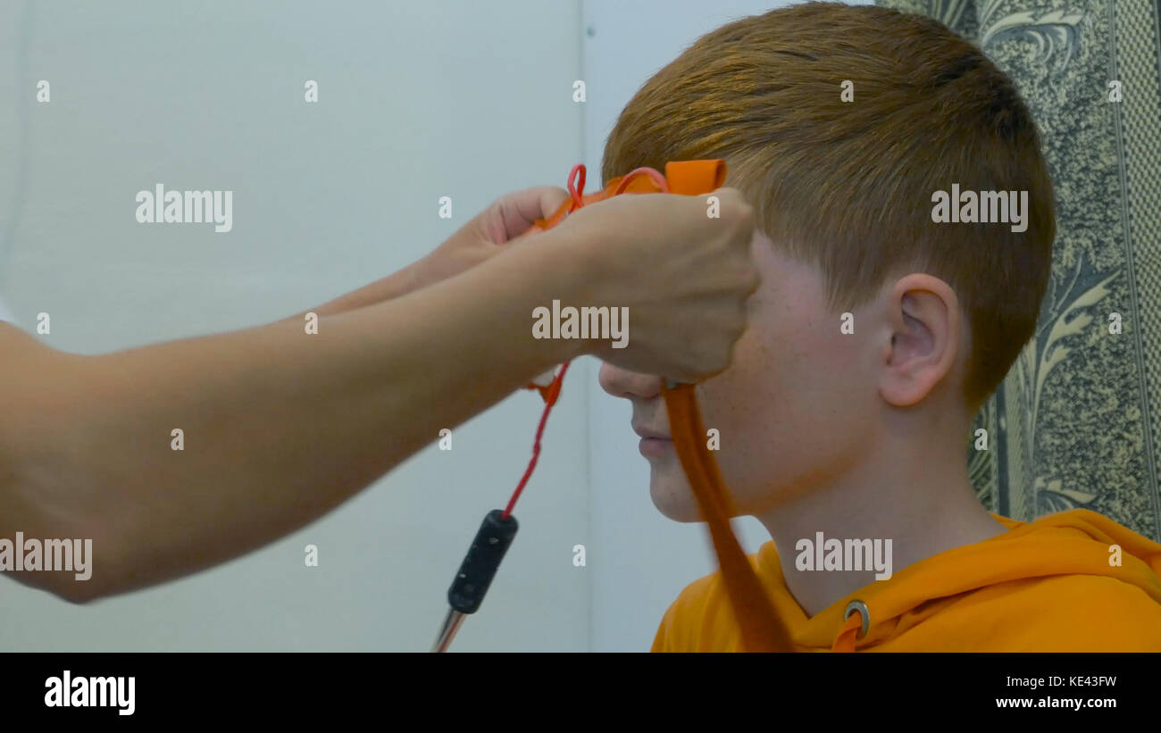 Europäisches Kinderführungs-Elektroenzephalogramm. Ein Prozessfragment. Rheoenzephalographie - ein Arzt bringt Elektroden am Kopf des Patienten an Stockfoto