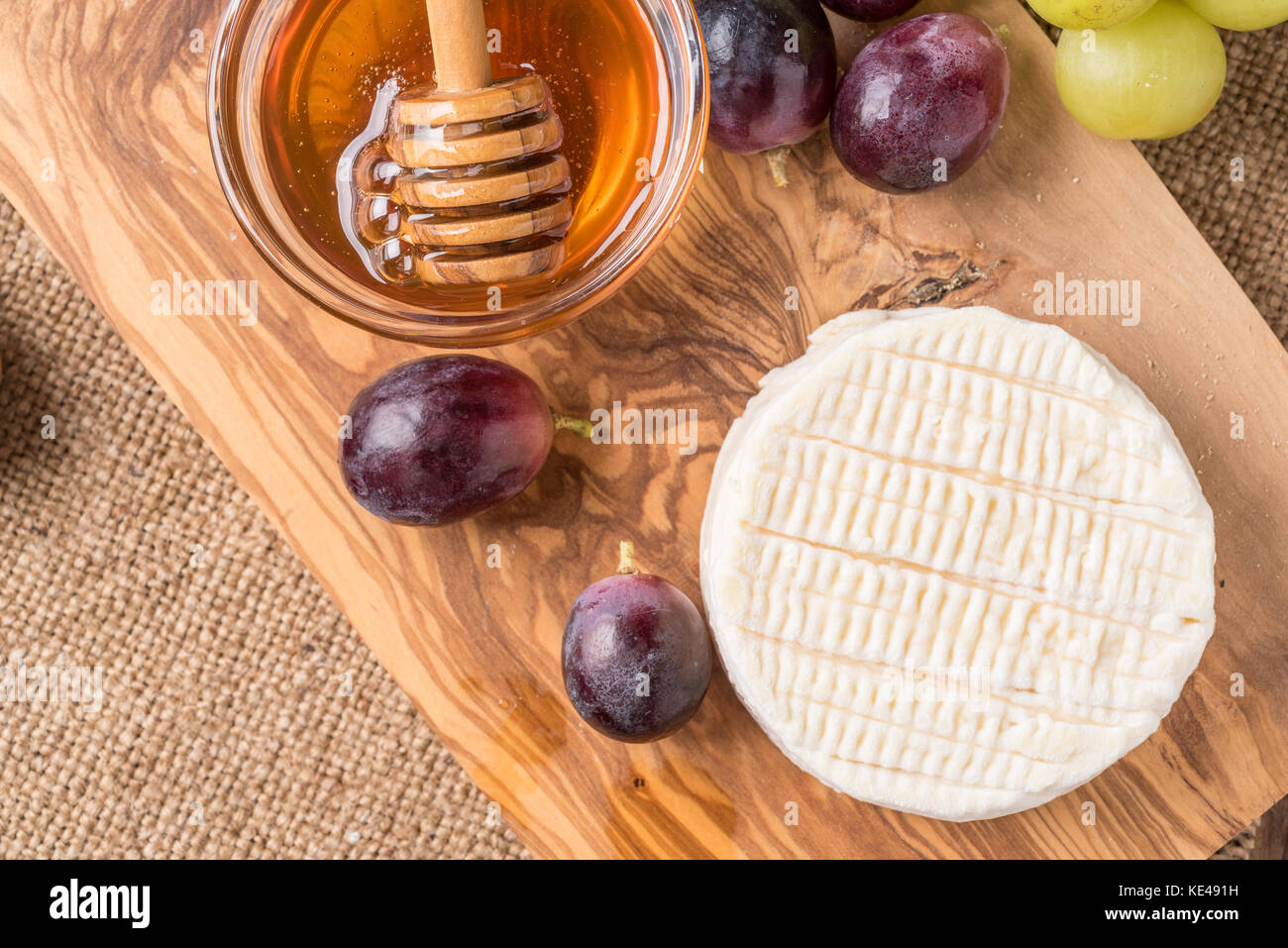 Holzbrett mit Käse, Trauben und Honig Stockfoto