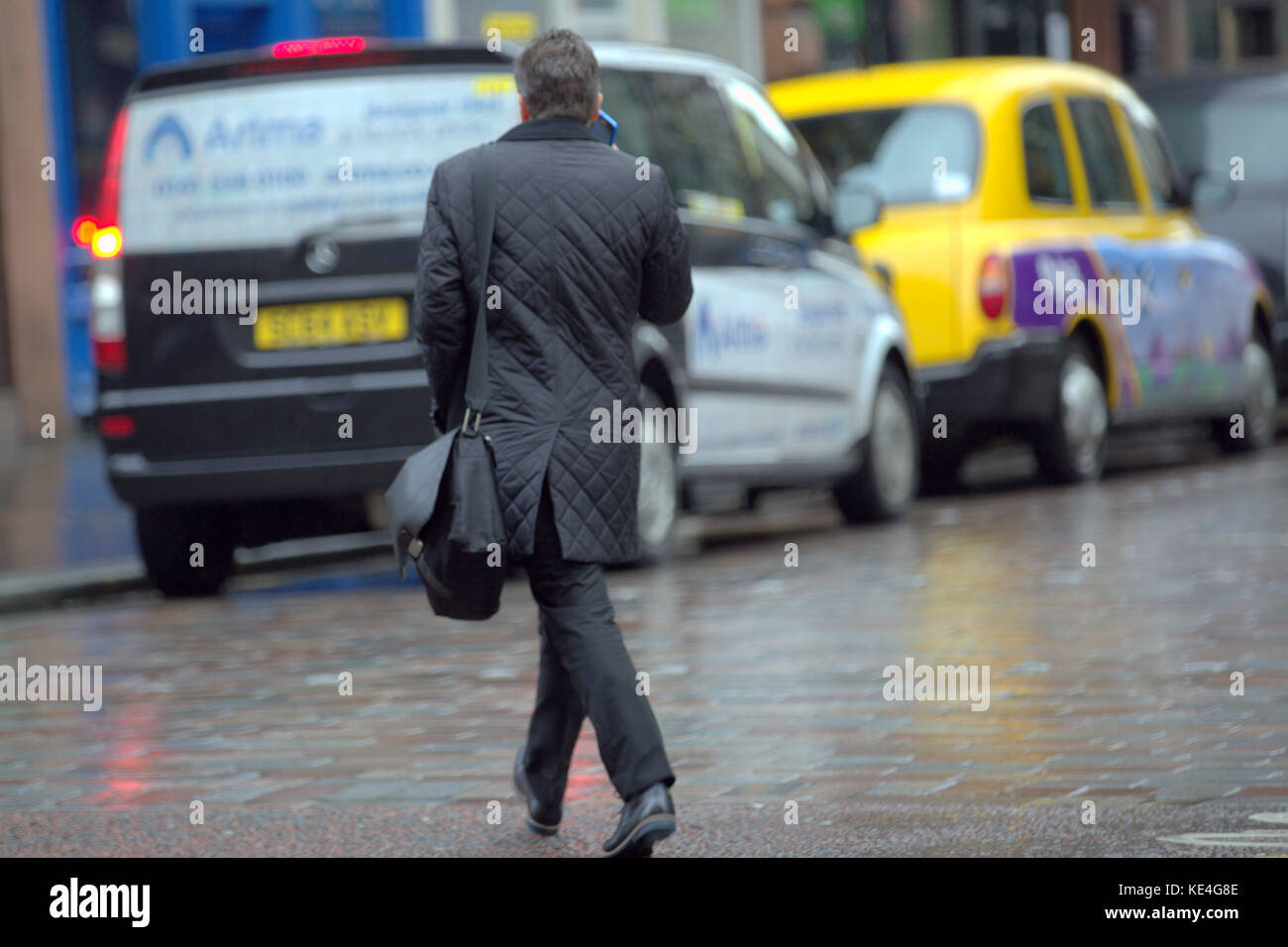 Geschäftsmann gekleidet am Telefon ein Taxi mit Mann Tasche Laptop bei nasser Straße regen Wetter Stockfoto