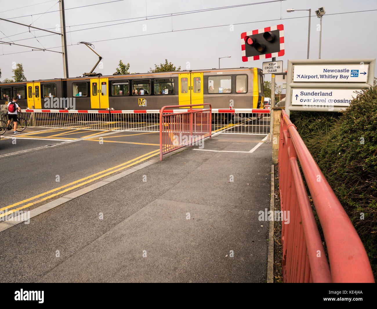 Eine elektrische Zug fährt entlang der Strecke über die Straße überqueren der Tyne und Wear metro bei East Boldon, England. Stockfoto