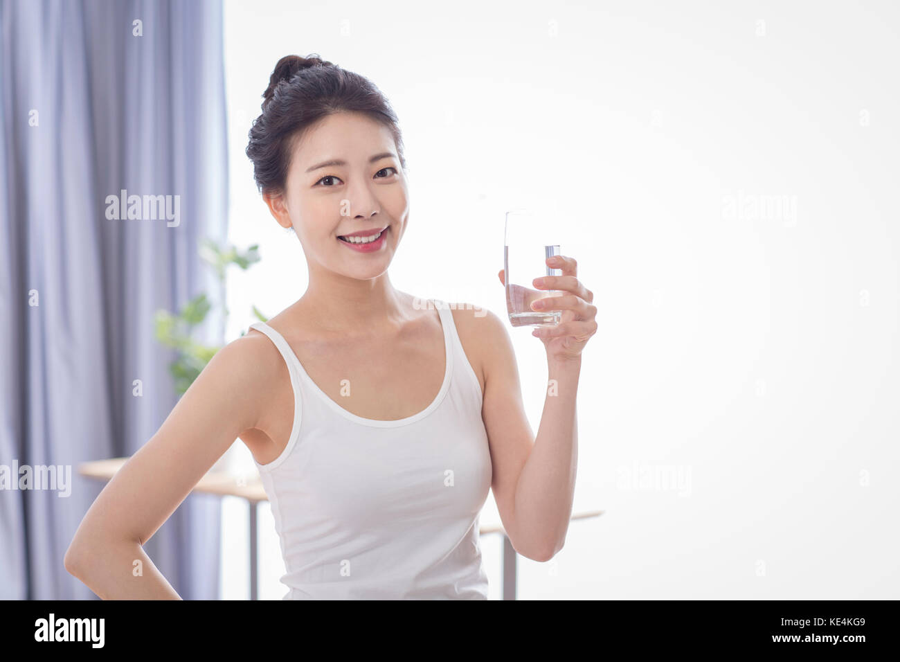 Portrait der junge lächelnde Frau mit einem Glas Wasser posing Stockfoto