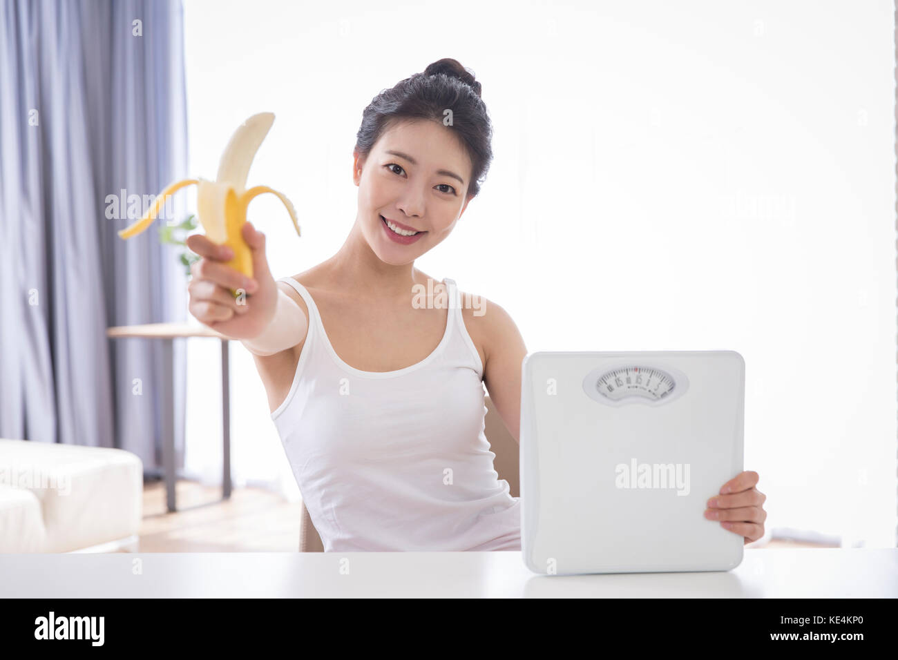 Portrait der junge lächelnde Frau mit Banane und Skala posing Stockfoto