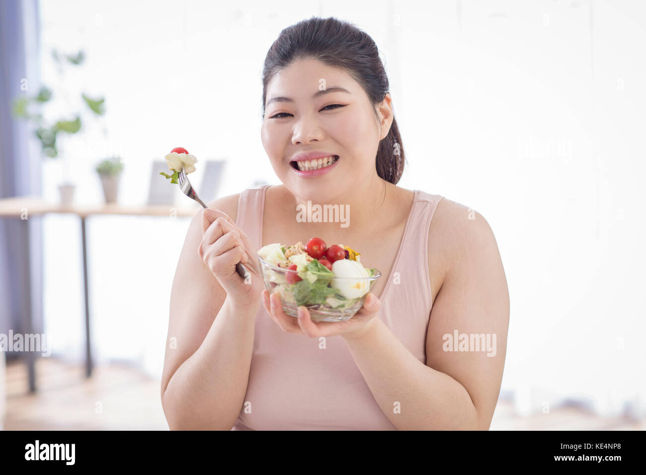 Portrait der junge lächelnde fette Frau mit einer Schüssel Salat Stockfoto