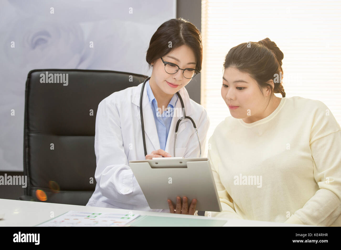 Portrait von Frau Doktor und fette Frau in einem Diagramm an Adipositas Klinik Stockfoto