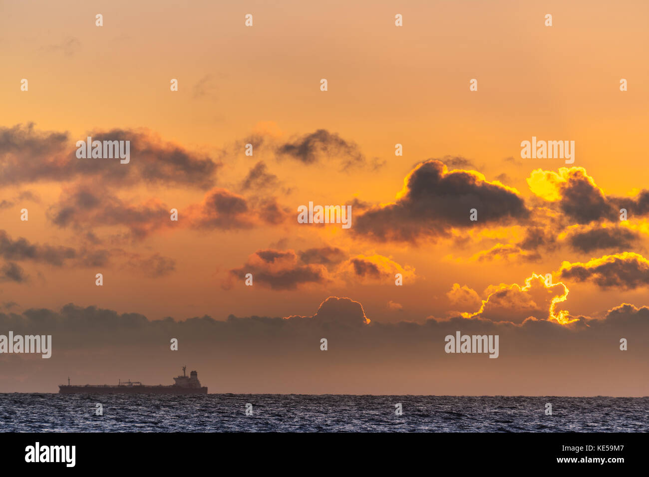 Ein großes Frachtschiff Köpfe heraus in die Nordsee wie die Sonne am Horizont steigt. Stockfoto