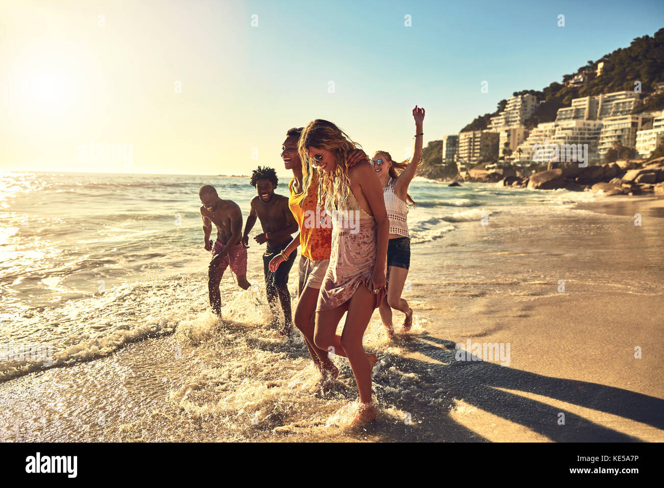 Spielerische junge Freunde, die im Sommer im sonnigen Meer surfen Stockfoto
