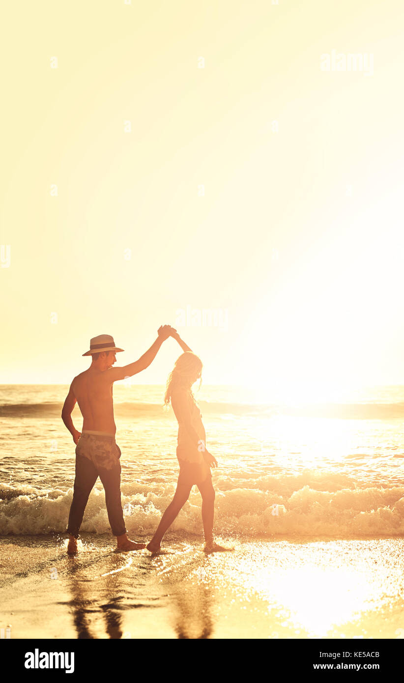 Junges Paar hält sich die Hände und läuft auf sonnigen Sommer Sonnenuntergang Ozean Strand Stockfoto