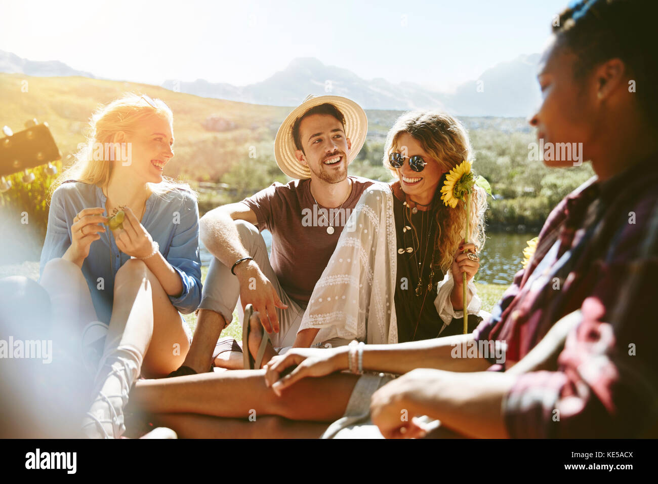 Lächelnde junge Freunde genießen Picknick im sonnigen Sommerpark Stockfoto