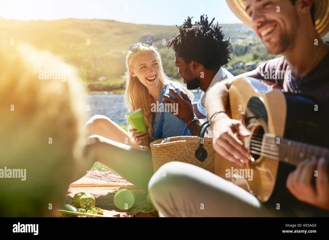 Junge Freunde spielen Gitarre und genießen sonnigen Sommer Picknick Stockfoto
