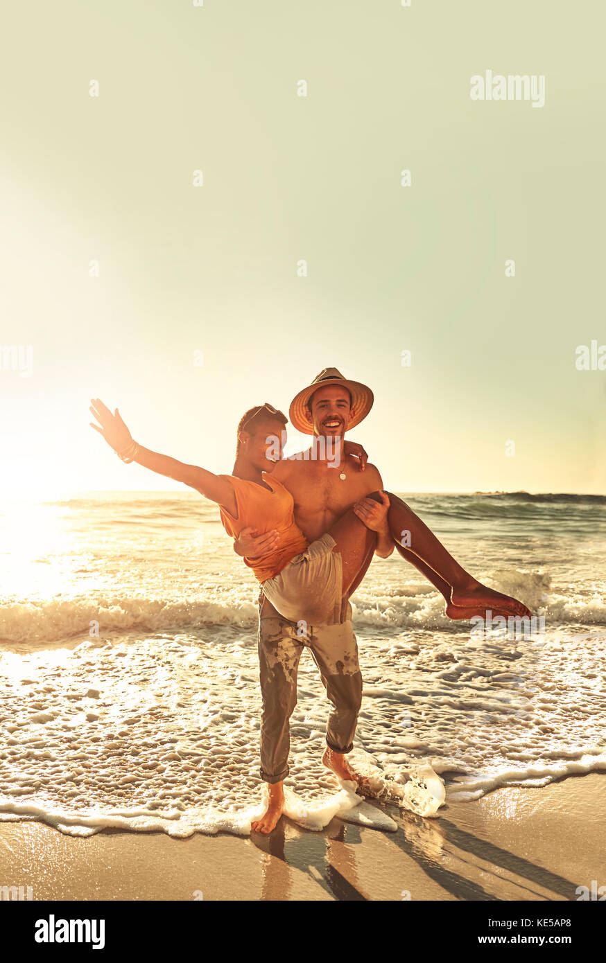 Portrait verspieltes junges Paar am sonnigen Sommerstrand am Meer Stockfoto