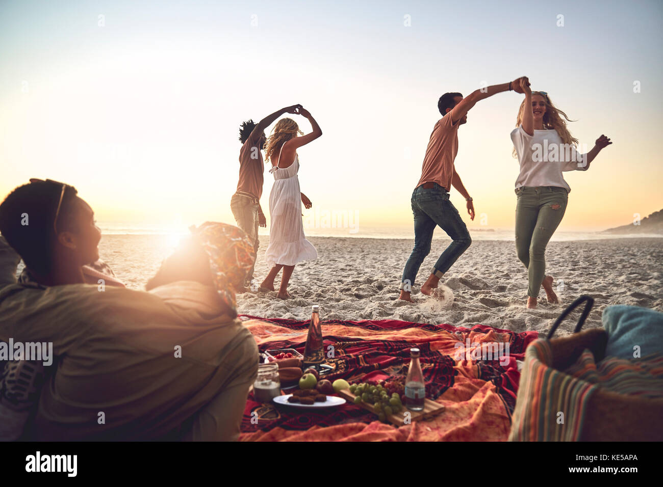 Junge Paare tanzen und genießen Picknick am Sommerstrand Stockfoto
