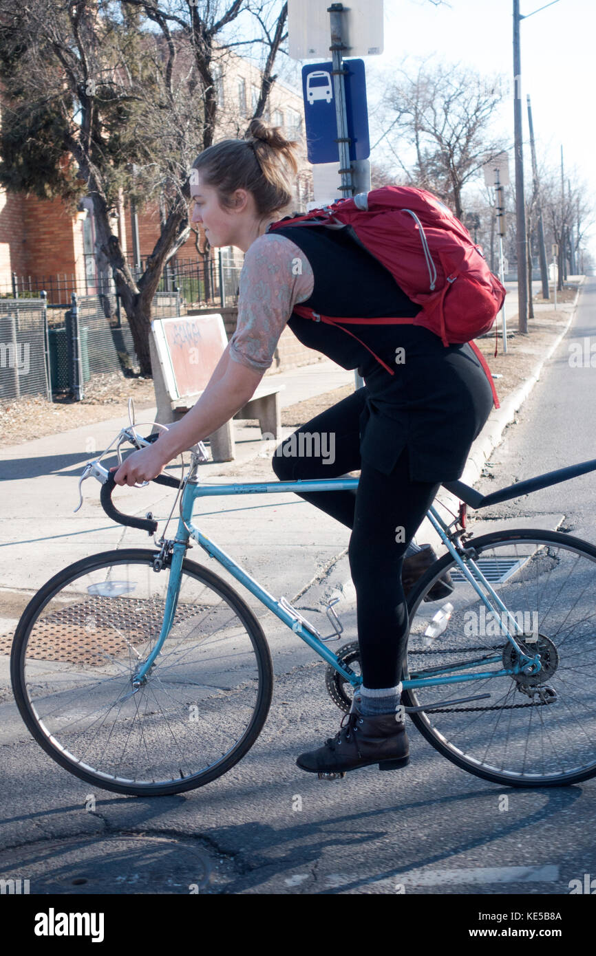 Junge gut gekleidete Frau, die ihr Fahrrad radeln entlang der Straße, die einen Rucksack. Minneapolis Minnesota mn Usa Stockfoto