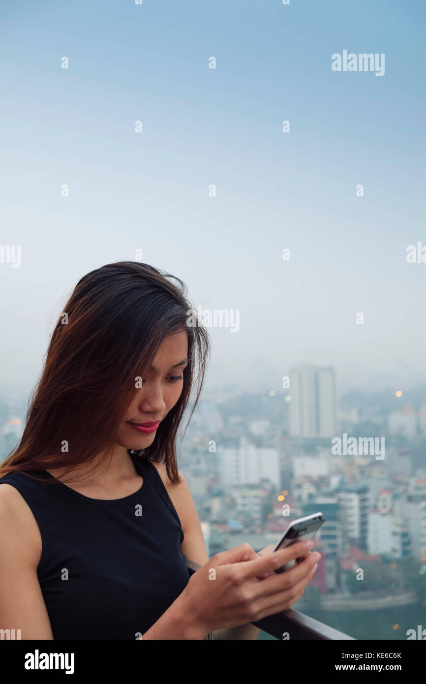 Junge asiatische Frau auf ihr Handy Stockfoto
