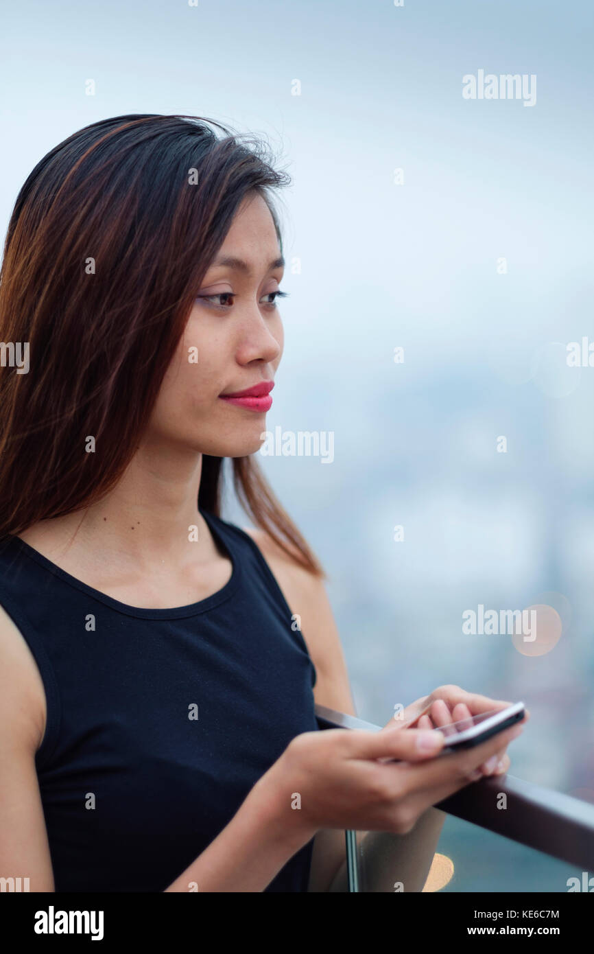 Junge asiatische Frau auf ihr Handy Stockfoto