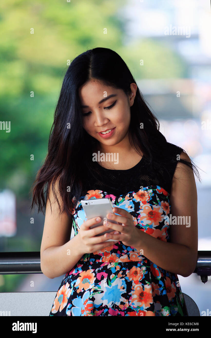 Junge asiatische Frau draußen Messaging auf Ihrem Smartphone Stockfoto