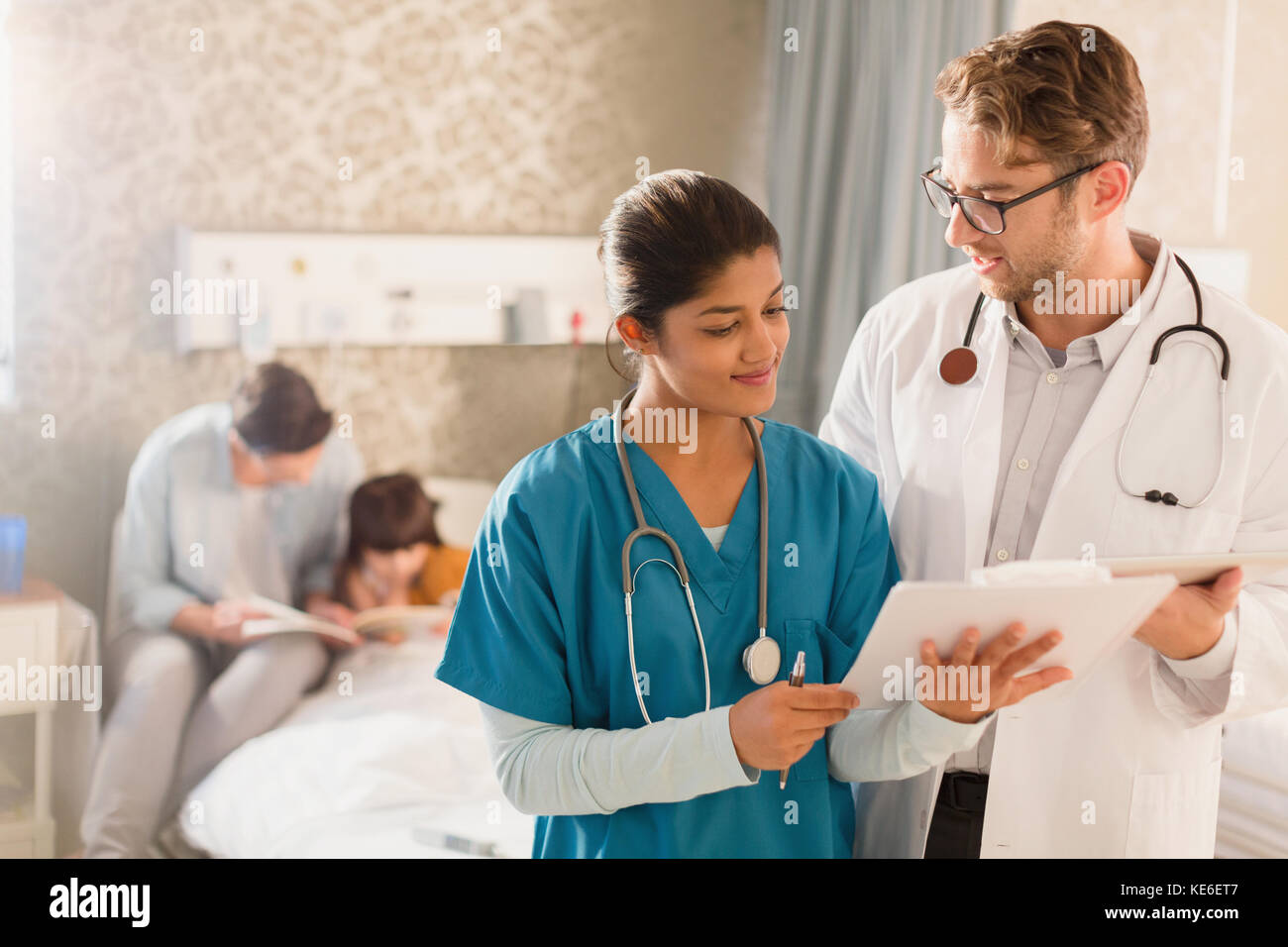 Arzt und Krankenschwester machen Runden im Krankenhaus, Überprüfung der Krankenakte auf Zwischenablage Stockfoto