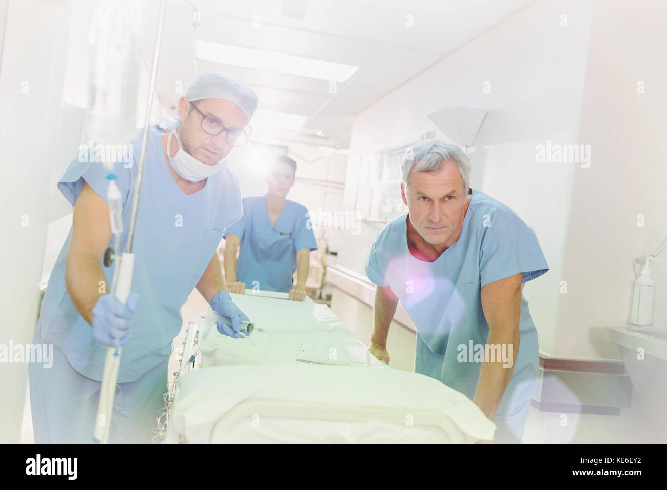 Entschlossene Chirurgen, die die Bahre über den Krankenhausflur schieben Stockfoto