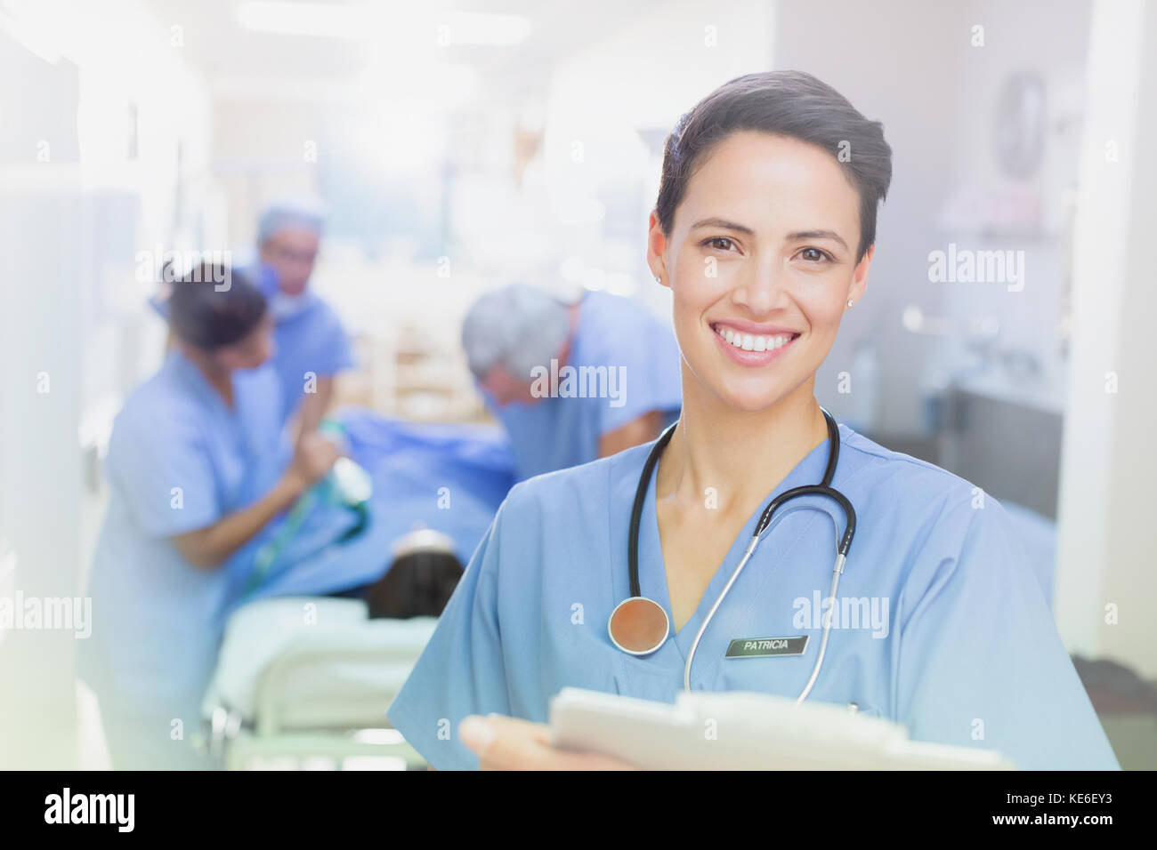 Portrait lächelnd, selbstbewusst weibliche Chirurg mit Zwischenablage im Krankenhaus Korridor Stockfoto