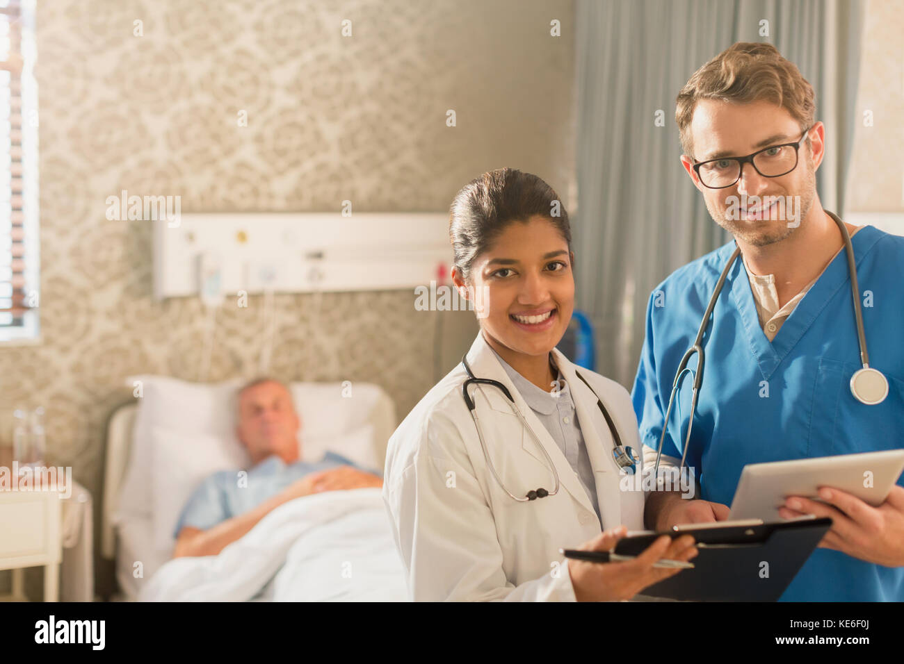 Porträt lächelnd, selbstbewusst Arzt und Krankenschwester machen Runden, mit digitalen Tablet und Zwischenablage im Krankenhauszimmer Stockfoto