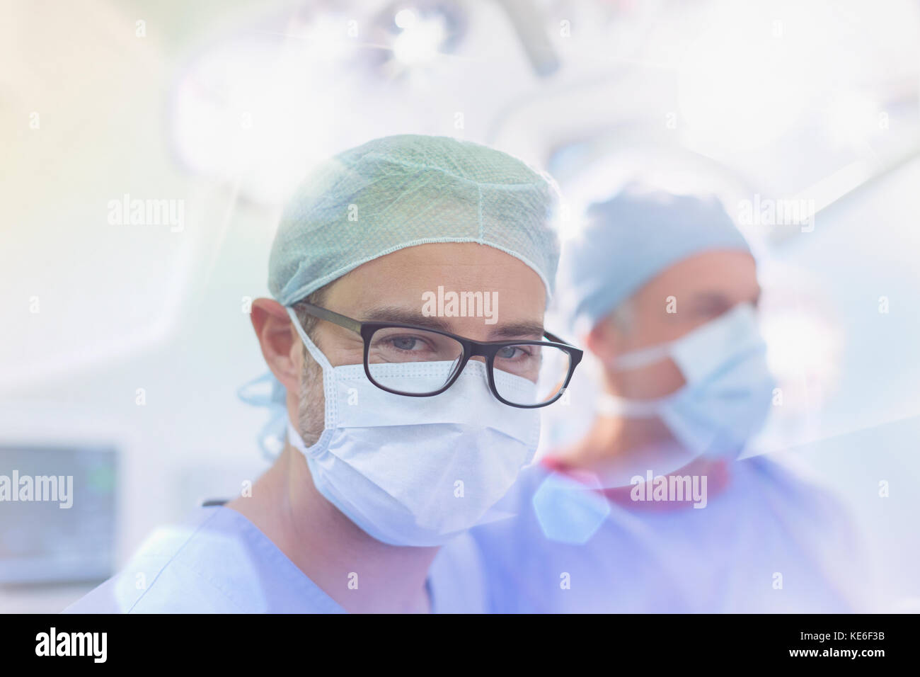 Portrait zuversichtlich männlichen Chirurgen trägt Brillen und chirurgische Maske in Operationssaal Stockfoto
