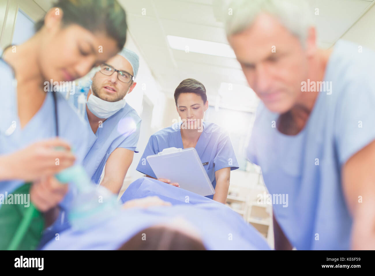 Chirurgen mit Zwischenablage schieben Patienten auf Trage im Krankenhaus Korridor Stockfoto