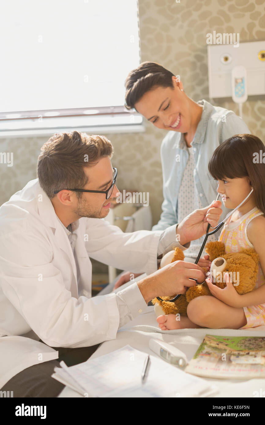 Männlicher Arzt zeigt Stethoskop zu Mädchen Patienten im Krankenhauszimmer Stockfoto