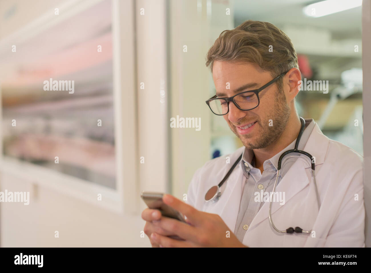 Männlicher Arzt SMS mit Handy im Krankenhaus Stockfoto