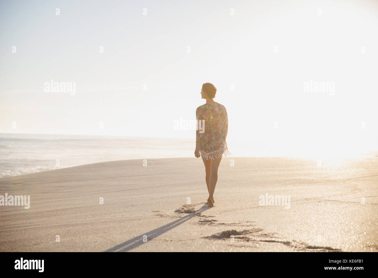 Nachdenkliche, ruhige Frau, die am sonnigen Sommerstrand spazieren geht Stockfoto