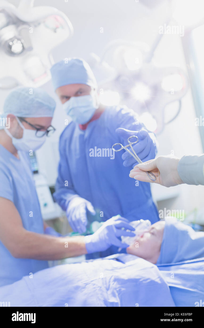 Chirurg greift nach einer chirurgischen Schere im Operationssaal Stockfoto