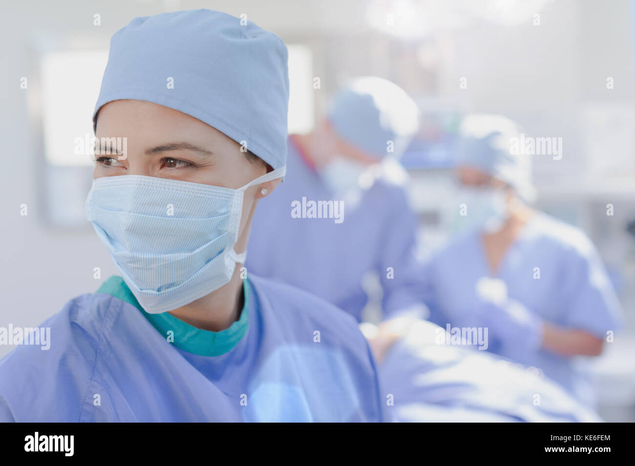 Lächelnde weibliche Chirurgen trägt chirurgische Maske im Operationssaal Stockfoto