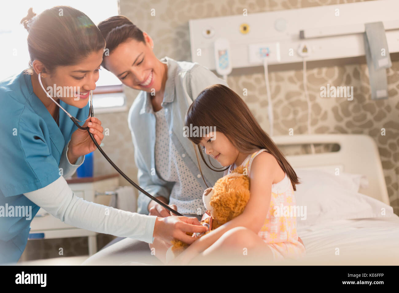 Weibliche Krankenschwester mit Stethoskop auf Teddybär von Mädchen Patientin Im Krankenhauszimmer Stockfoto