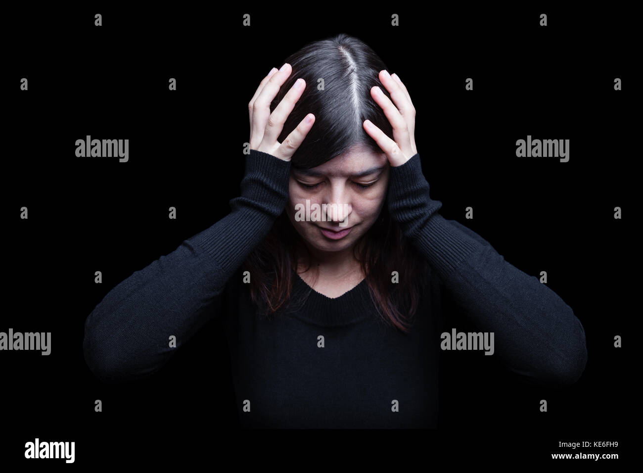 Distressed Frau mit dem Kopf mit den Händen auf einem schwarzen oder dunklen Hintergrund. Migräne Kopfschmerzen schmerzen Depression leiden, Verzweiflung gedrückt traurig Trauer Stockfoto
