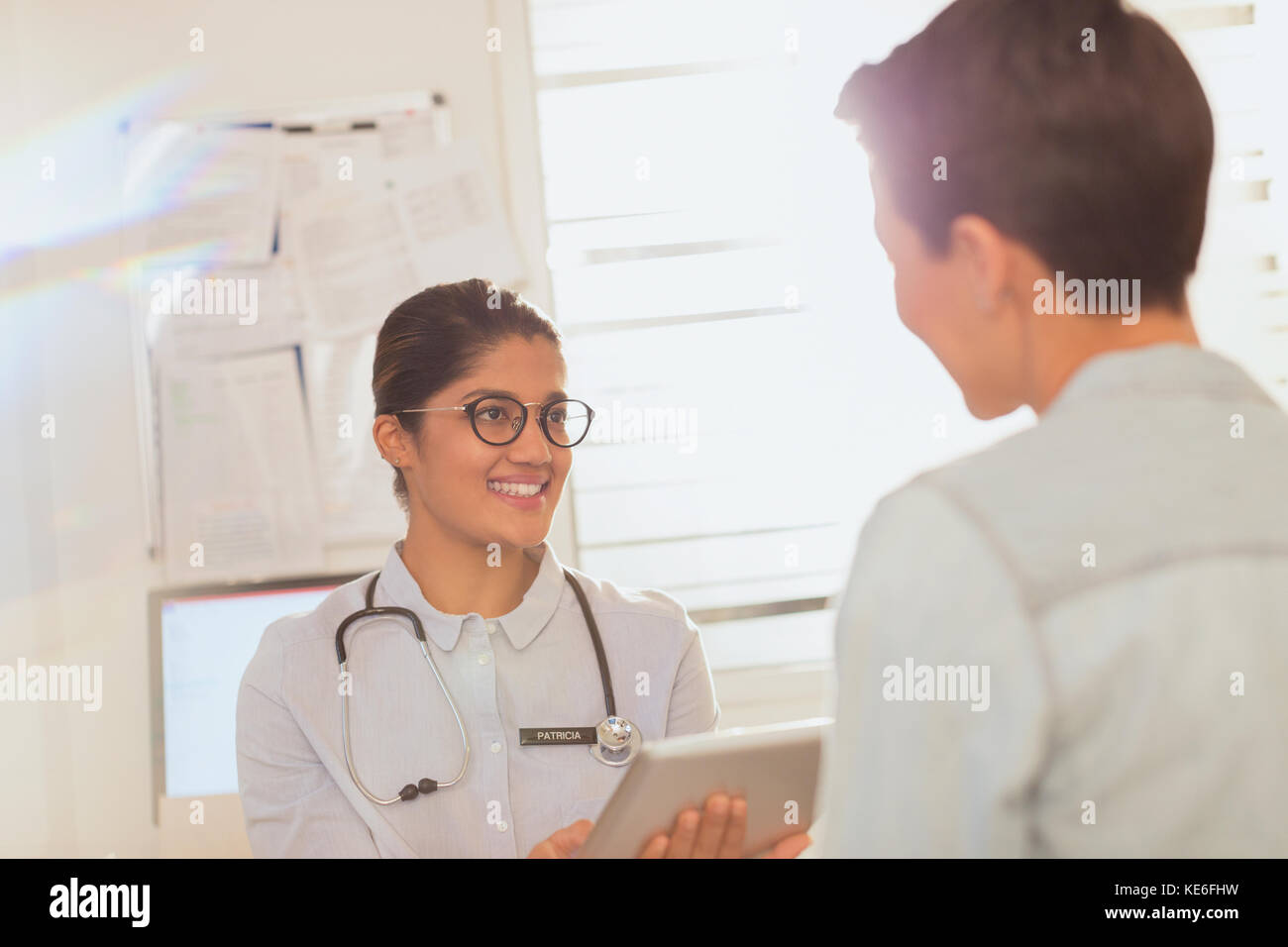 Ärztin mit digitaler Tablette im Gespräch mit dem Patienten bei der Untersuchung Zimmer Stockfoto