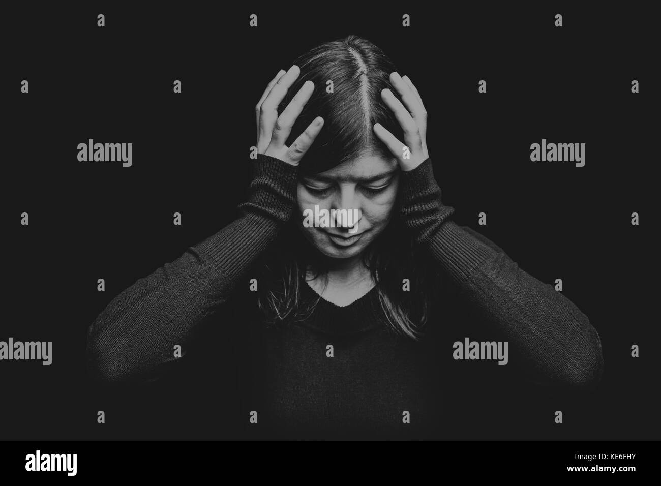 Distressed Frau mit dem Kopf mit den Händen auf einem schwarzen oder dunklen Hintergrund. Migräne Kopfschmerzen schmerzen Depression leiden, Verzweiflung gedrückt traurig Trauer Stockfoto
