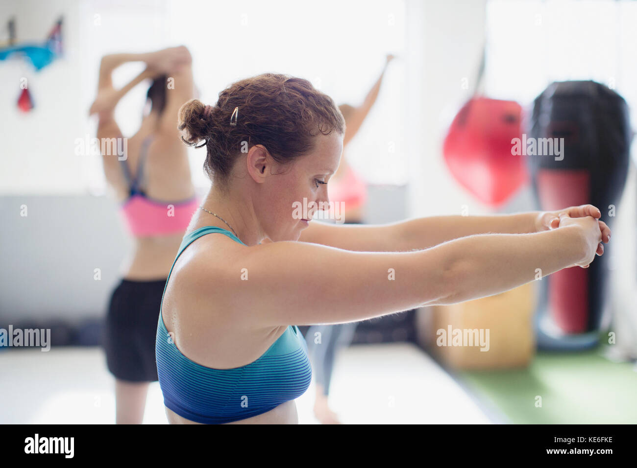 Fokussierte weibliche Boxerin, die die Arme im Fitnessstudio streckt Stockfoto