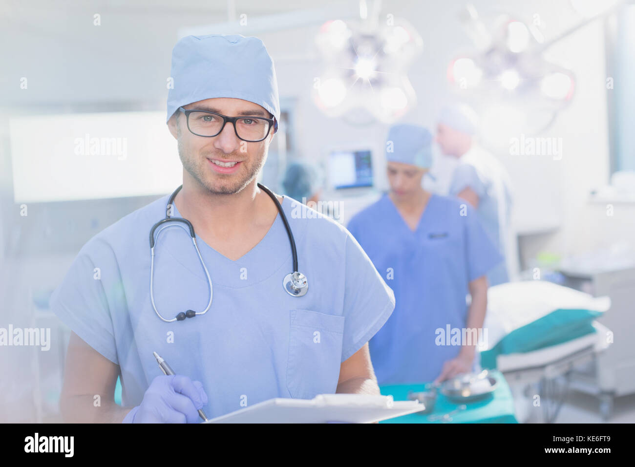 Portrait junger männlicher Chirurg in Brillen mit Klemmbrett in Betrieb Zimmer Stockfoto