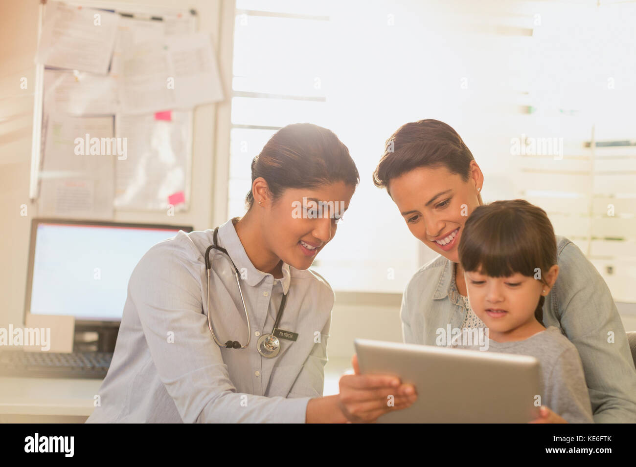 Kinderärztin zeigt digitales Tablet für Mädchen und Mutter Im Untersuchungsraum Stockfoto