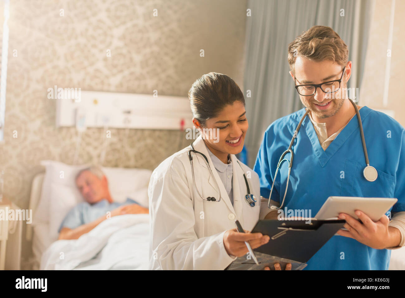 Ärztin und Krankenschwester machen Runden, mit digitalem Tablet und Zwischenablage im Krankenhaus Stockfoto