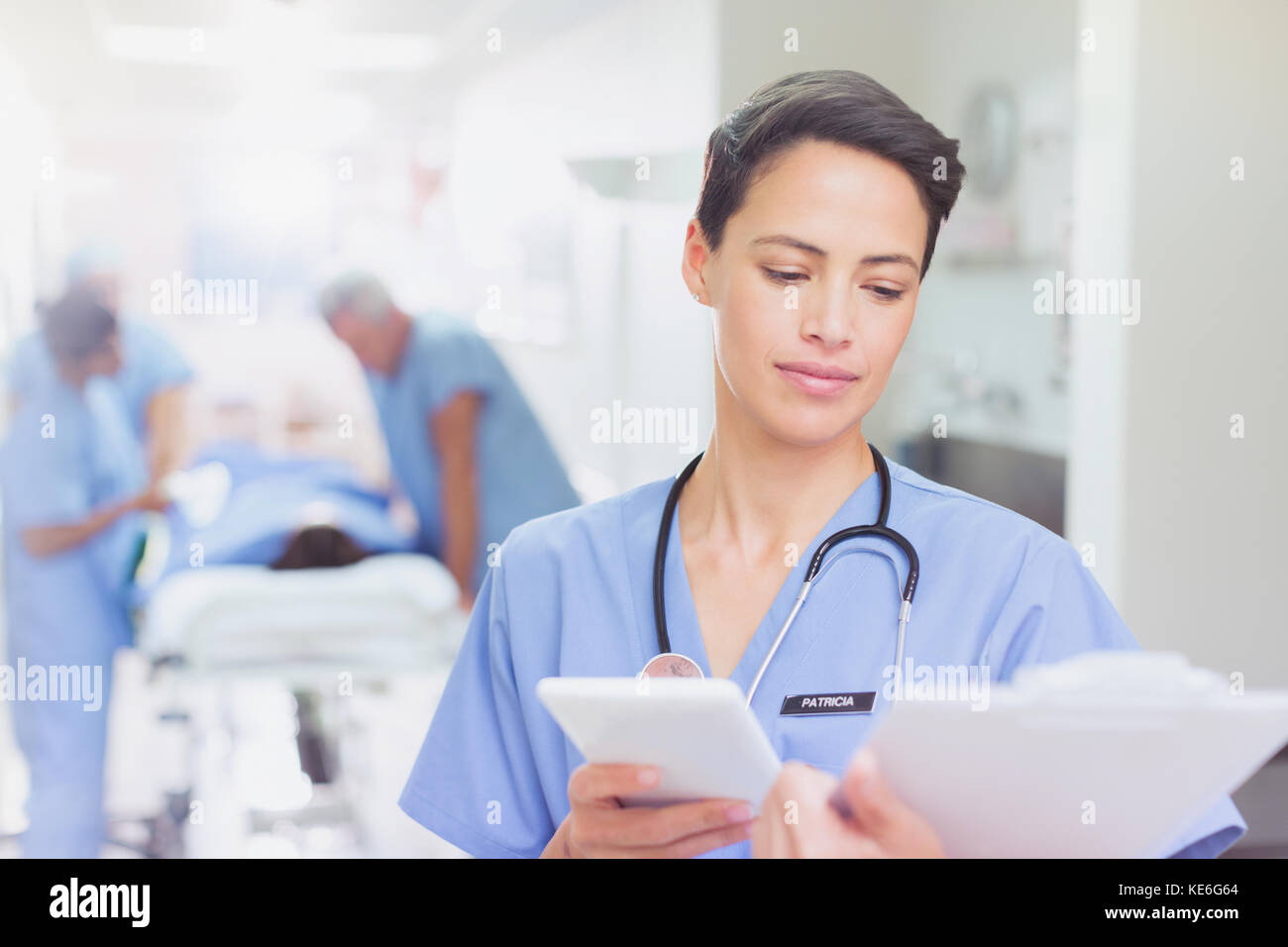 Weibliche Chirurg mit digitalen Tablette Überprüfung Zwischenablage Papierkram im Krankenhaus Korridor Stockfoto