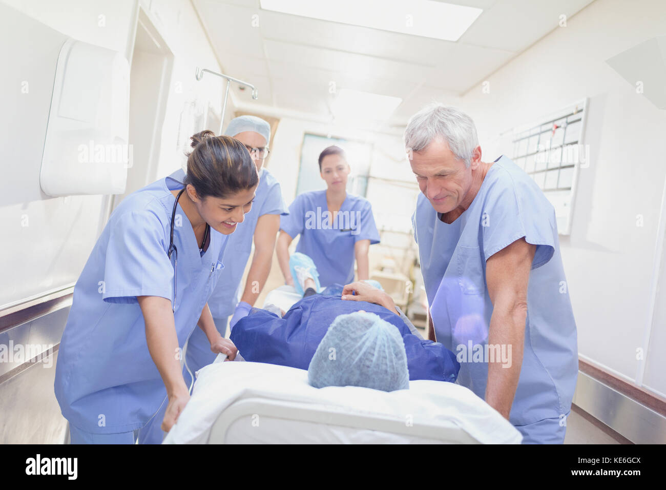 Fürsorgliche Chirurgen, die den Patienten auf eine Bahre im Krankenhausflur schieben Stockfoto