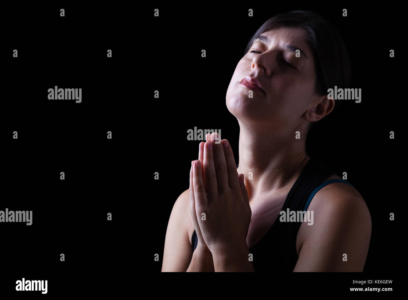 Treue Frau beten und das Gefühl der Präsenz oder von Gott berührt. die Hände gefaltet im Gottesdienst, Kopf und Augen geschlossen. Stockfoto